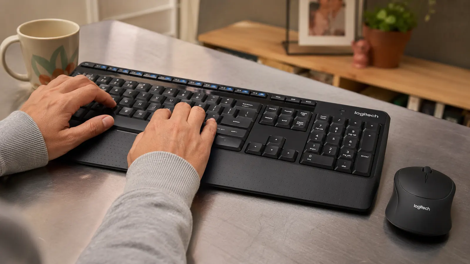 Close-up of hands typing on the Logitech MK345 keyboard showing the padded palm rest in use